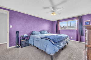 Bedroom with a textured ceiling, ceiling fan, and light colored carpet