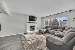 Living room featuring track lighting, a brick fireplace, and a textured ceiling