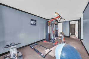 Workout area with a textured ceiling and crown molding