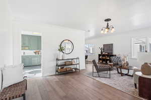 Living room featuring hardwood / wood-style floors, ornamental molding, and a notable chandelier