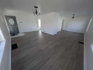 Living room featuring dark LVP flooring, an inviting chandelier, and ornamental molding