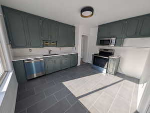 Kitchen with new appliances with stainless steel finishes, tile patterned floors, and sink