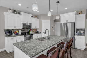 Kitchen with sink, pendant lighting, a center island with sink, and stainless steel appliances