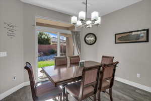 Dining space with dark hardwood / wood-style flooring and a notable chandelier