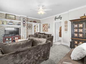 Living room featuring light carpet, ceiling fan, and ornamental molding