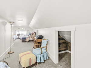 Living area with light carpet and vaulted ceiling