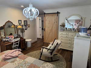 Bedroom featuring a chandelier, engineered hard wood, crown molding, and a barn door