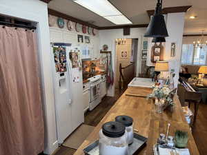 Kitchen with white cabinets, an inviting chandelier, sink, and white appliances