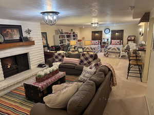 Living room with a textured ceiling, a large fireplace, light carpet, and a chandelier