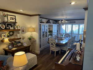 Dining space with engineered hard wood, a chandelier, and ornamental molding