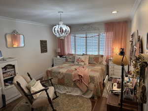 Bedroom featuring an inviting chandelier, crown molding, and engineered hard wood