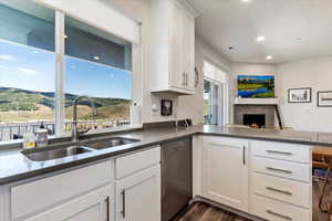 Kitchen with white cabinetry, a mountain view, kitchen peninsula, dishwasher, and sink