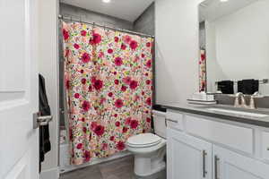 Full bathroom featuring toilet, vanity, and shower / bathtub combination with curtain