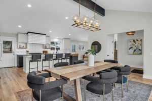 Open dining room with light hardwood / wood-like flooring, vaulted ceilings and modern finishes