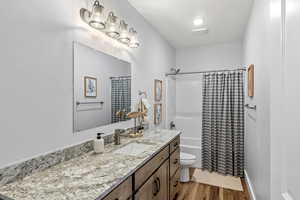 Full bathroom with toilet, vanity, shower / bath combo, and hardwood / wood-style flooring