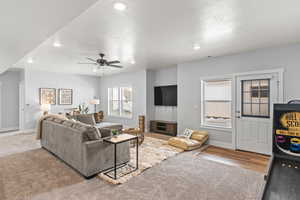 Carpeted living room with a textured ceiling and ceiling fan