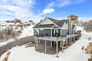 Snow covered back of property with a deck