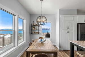 Dining area with a water view, a notable chandelier, a wealth of natural light, and light hardwood / wood-style floors