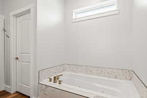 Bathroom featuring tiled bath and wood-type flooring