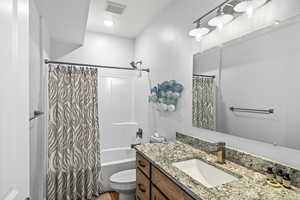 Full bathroom with toilet, vanity, and shower / bath combo with shower curtain