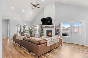 Living room with a large fireplace, plenty of natural light, and high vaulted ceiling