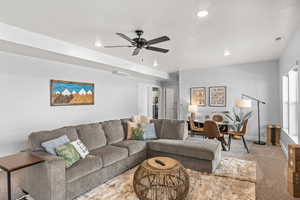 Carpeted living room featuring ceiling fan