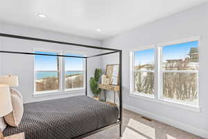 Bedroom with light carpet and a water view