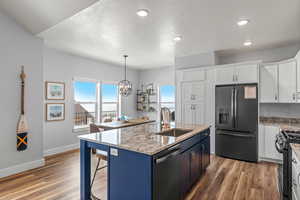 Kitchen featuring appliances with stainless steel finishes, sink, white cabinetry, and a center island with sink