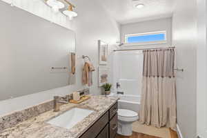 Full bathroom with a textured ceiling, hardwood / wood-style floors, vanity, toilet, and shower / tub combo with curtain