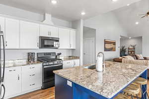 Kitchen featuring white cabinetry, appliances with stainless steel finishes, a kitchen island with sink, and a breakfast bar area