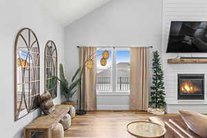 Living area featuring light hardwood / wood-style floors, a large fireplace, and lofted ceiling