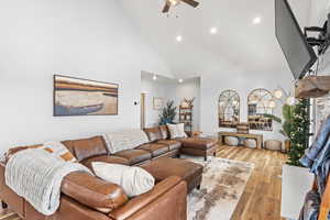 Living room with high vaulted ceiling, light hardwood / wood-style floors, and ceiling fan