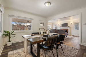 Dining area featuring dark hardwood / wood-style flooring, crown molding, and a fireplace