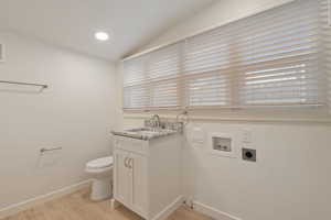 Bathroom featuring toilet, lofted ceiling, hardwood / wood-style floors, and vanity