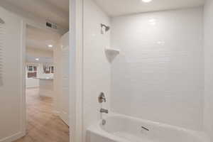 Bathroom featuring tiled shower / bath combo and hardwood / wood-style flooring