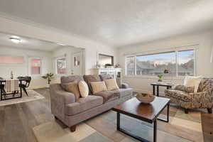 Living room featuring hardwood / wood-style flooring, plenty of natural light, a textured ceiling, and crown molding