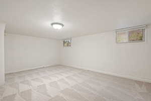 Basement with a textured ceiling and light carpet