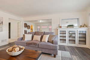 Living room featuring dark wood-type flooring and ornamental molding