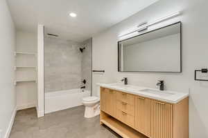 Full bathroom featuring toilet, tiled shower / bath, vanity, tile patterned floors, and a textured ceiling