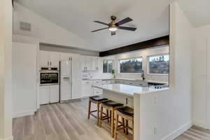 Kitchen featuring sink, a kitchen breakfast bar, white appliances, and white cabinetry