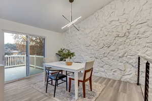 Dining space with lofted ceiling, an inviting chandelier, and hardwood / wood-style flooring