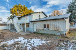 Snow covered back of property featuring a deck and a patio