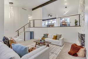 Living room featuring ceiling fan with notable chandelier, light colored carpet, and vaulted ceiling with beams