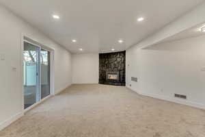 Unfurnished living room with a stone fireplace and carpet flooring