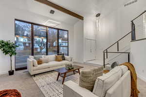 Carpeted living room featuring vaulted ceiling with beams