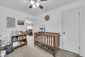 Bedroom featuring ceiling fan, carpet, ornamental molding, and a crib