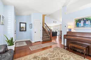 Entryway with vaulted ceiling, crown molding, and dark hardwood / wood-style floors