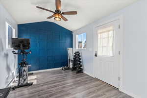 Workout area with vaulted ceiling, ceiling fan, and hardwood / wood-style flooring