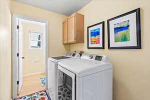 Washroom featuring cabinets, independent washer and dryer, and light wood-type flooring