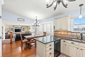 Kitchen featuring decorative light fixtures, cream cabinetry, dishwasher, and sink